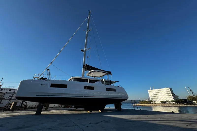 Almissa Yacht Photos Pics 2023 Lagoon 46 catamaran docked, showcasing sleek design and modern features against a clear blue sky.
