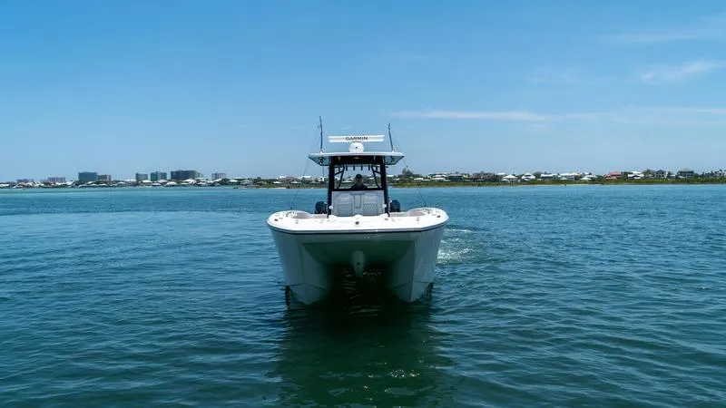  Yacht Photos Pics 2024 Invincible 40' Catamaran on calm waters with cityscape in the background.