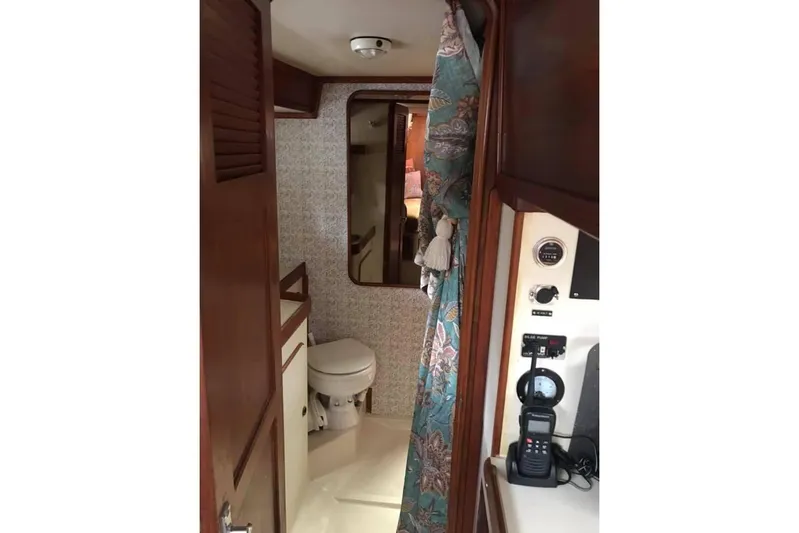 Pacific High Yacht Photos Pics Interior of 1983 Stuart Marine 62 Custom Ketch, featuring a compact bathroom and floral curtain.