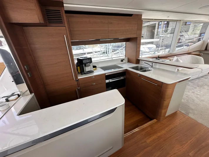  Yacht Photos Pics Modern kitchen interior on 2022 Princess Y72 yacht, featuring sleek wood cabinetry and white countertops.