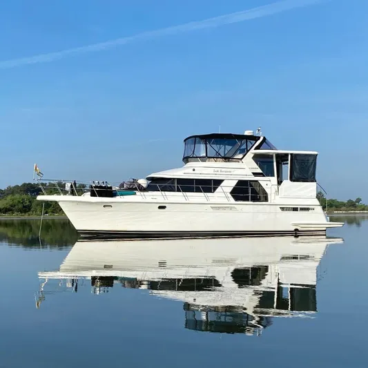Irish Hurricane Yacht Photos Pics 1998 Carver 445 Aft Cabin Motor Yacht reflecting on calm water under clear blue sky.