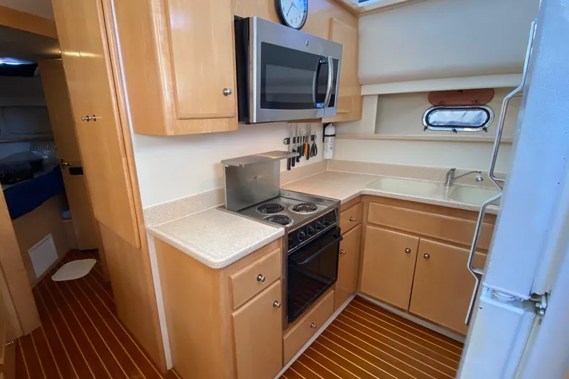 Irish Hurricane Yacht Photos Pics 1998 Carver 445 Aft Cabin Motor Yacht kitchen with stove, microwave, and wooden cabinetry.