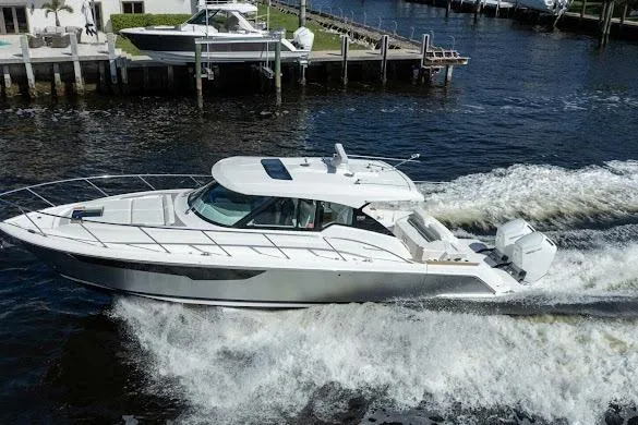  Yacht Photos Pics 2022 Tiara Sport 43 LE luxury boat cruising on a waterway near a dock.
