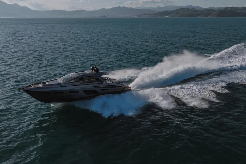 M/y "ghep" Yacht Photos Pics 2022 Pershing 7X yacht cruising swiftly on open sea with scenic mountain backdrop.