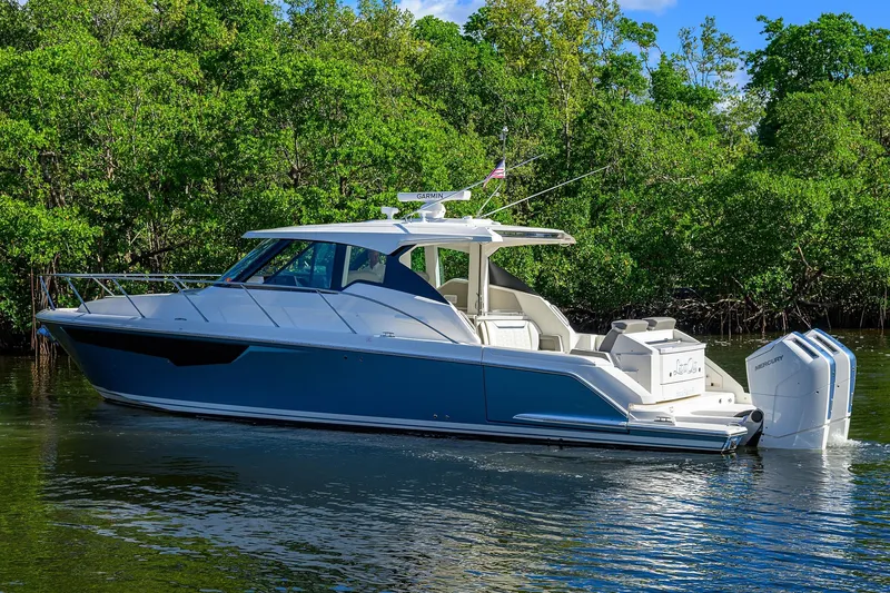 Let It Out Yacht Photos Pics 2022 Tiara Yachts 43 LE in water, surrounded by lush greenery.