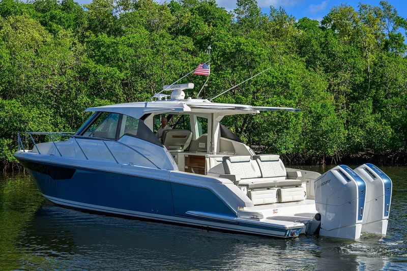Let It Out Yacht Photos Pics 2022 Tiara Yachts 43 LE cruising on a serene waterway with lush greenery.