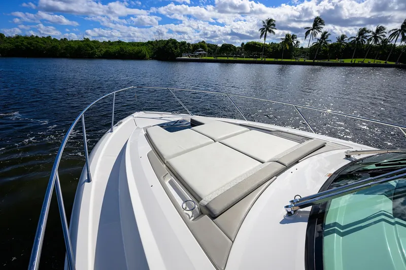 Let It Out Yacht Photos Pics 2022 Tiara Yachts 43 LE on serene water with sunpad and palm trees.