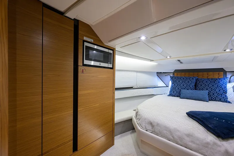Let It Out Yacht Photos Pics Luxurious 2022 Tiara Yachts 43 LE cabin interior with modern wood paneling and cozy bedding.