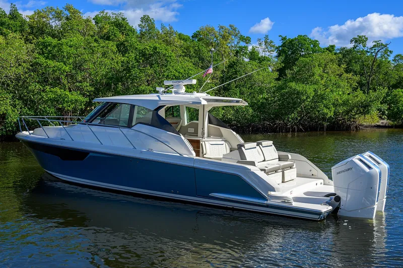 Let It Out Yacht Photos Pics 2022 Tiara Yachts 43 LE luxury boat on calm water, surrounded by lush greenery.