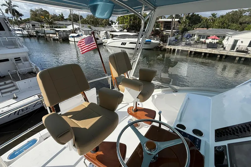One Life Yacht Photos Pics Helm of 2000 Hatteras 50 Convertible yacht with American flag, docked in marina.