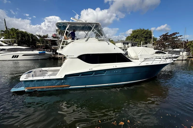One Life Yacht Photos Pics 2000 Hatteras 50 Convertible yacht docked in a marina under a partly cloudy sky.