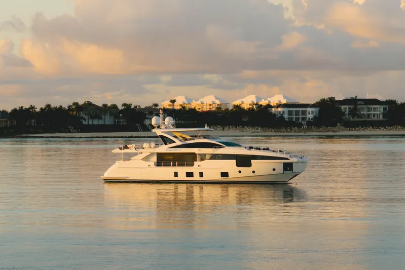 Carpe Diem Yacht Photos Pics Luxurious 2023 Azimut yacht on calm water at sunset, with coastal homes in the background.