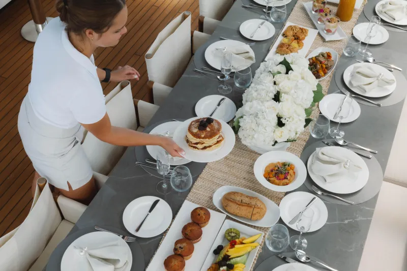 Carpe Diem Yacht Photos Pics Elegant dining setup on Azimut yacht, featuring gourmet dishes and floral centerpiece, 2023.