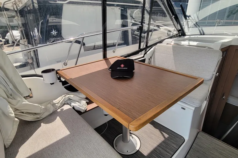 Tagwood Bbq Yacht Photos Pics 2023 Jeanneau NC 895 interior with table, seating, and branded cap.