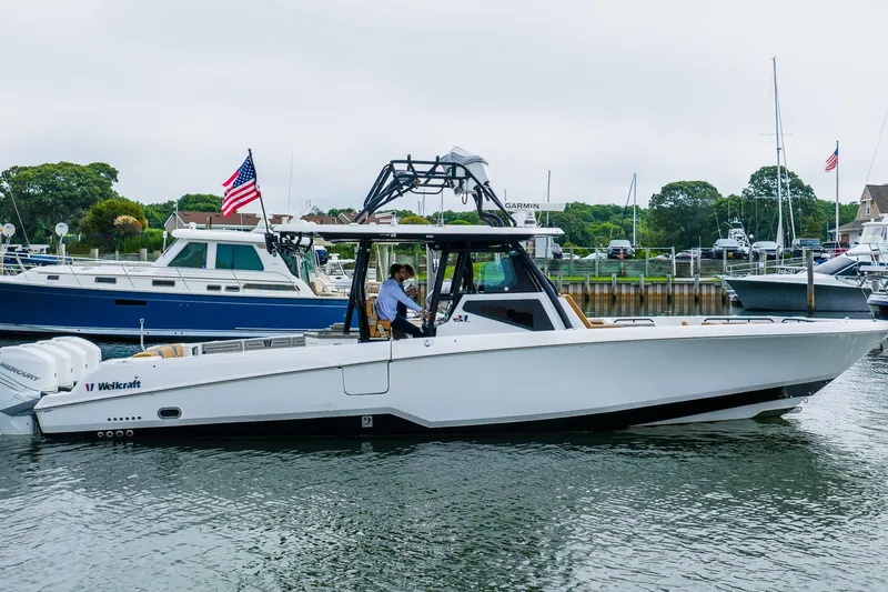  Yacht Photos Pics 2021 Wellcraft 402 Fisherman boat on water, with American flag, docked in marina.