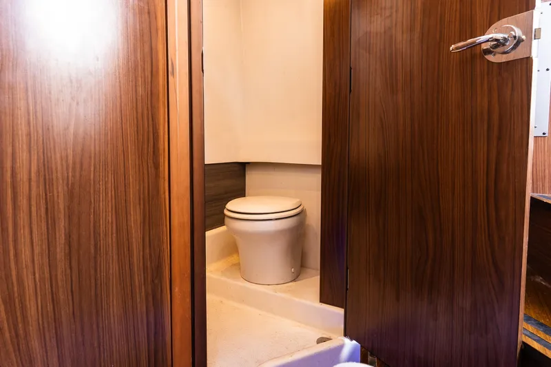  Yacht Photos Pics 2021 Wellcraft 402 Fisherman boat bathroom with wooden door and compact toilet.