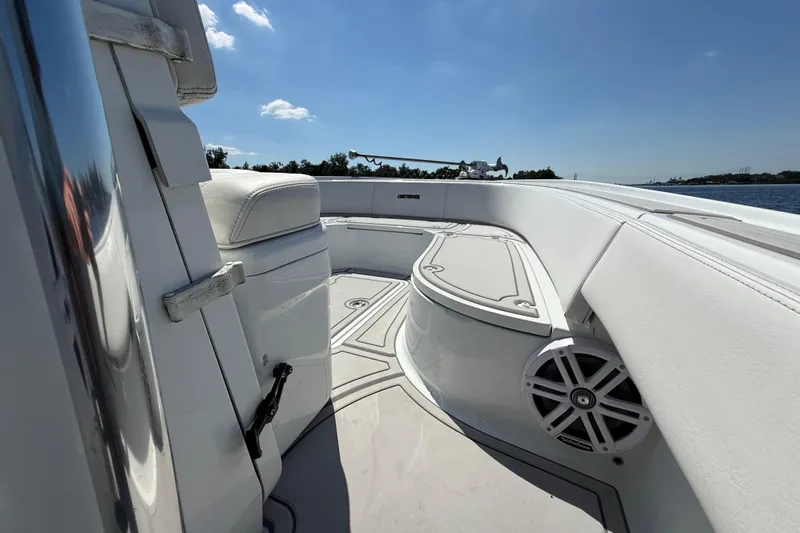  Yacht Photos Pics 2024 Contender 26 Bay boat interior with white seating and speaker, under clear blue sky.