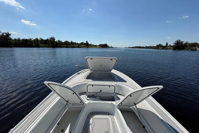  Yacht Photos Pics 2024 Contender 26 Bay boat with open storage compartments on a calm lake.