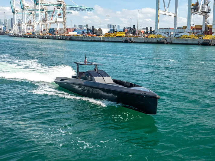  Yacht Photos Pics Sleek 2012 Wally 43 yacht cruising in a busy harbor with industrial backdrop.
