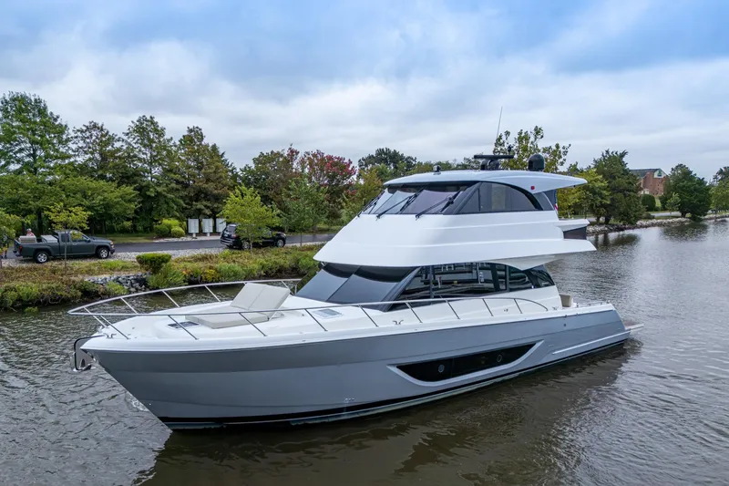 Norfolk Girl Yacht Photos Pics 2023 Maritimo M55 yacht cruising on a serene waterway, surrounded by lush greenery.