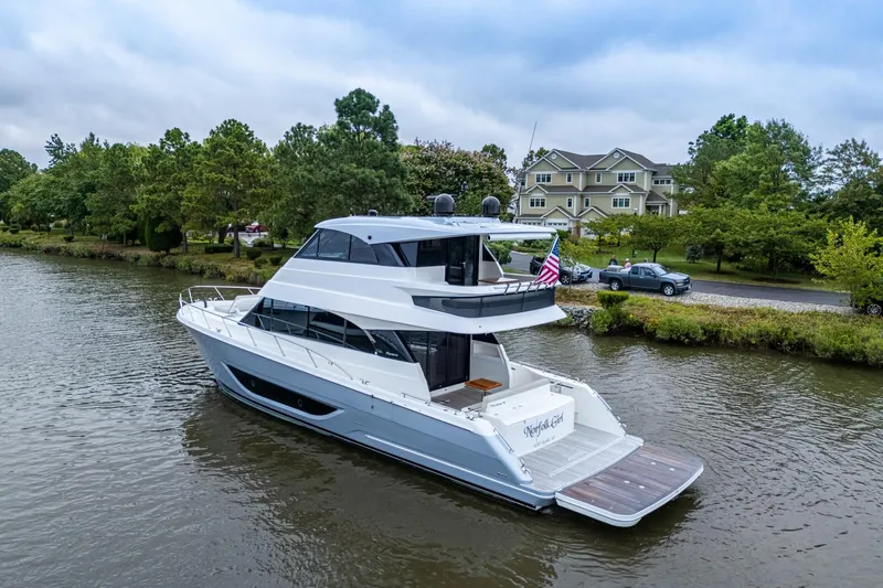 Norfolk Girl Yacht Photos Pics 2023 Maritimo M55 yacht cruising on a serene river near lush greenery and houses.
