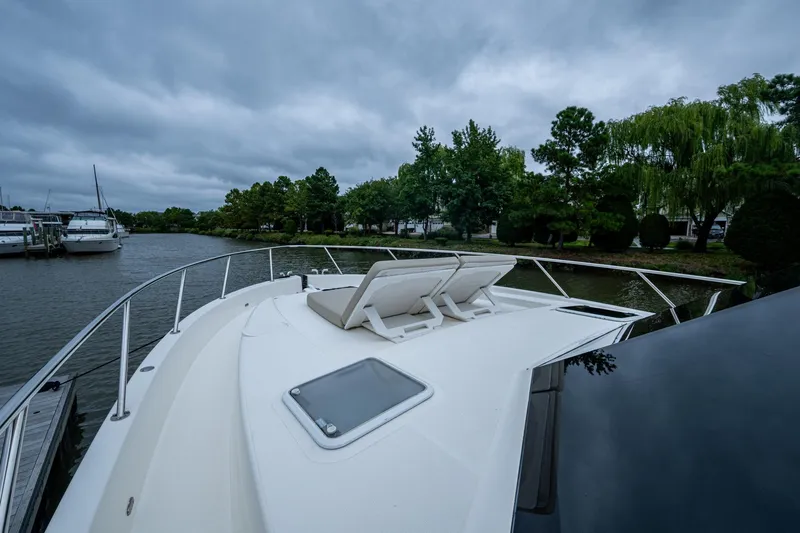 Norfolk Girl Yacht Photos Pics 2023 Maritimo M55 yacht on a serene river with lush greenery.