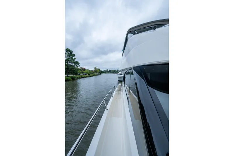 Norfolk Girl Yacht Photos Pics 2023 Maritimo M55 yacht cruising on a serene river under cloudy skies.
