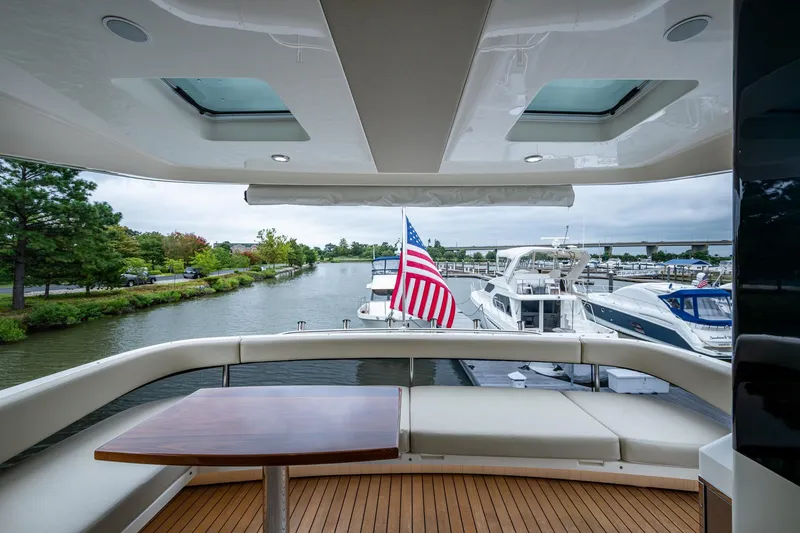Norfolk Girl Yacht Photos Pics 2023 Maritimo M55 yacht deck with seating, table, and American flag in marina.