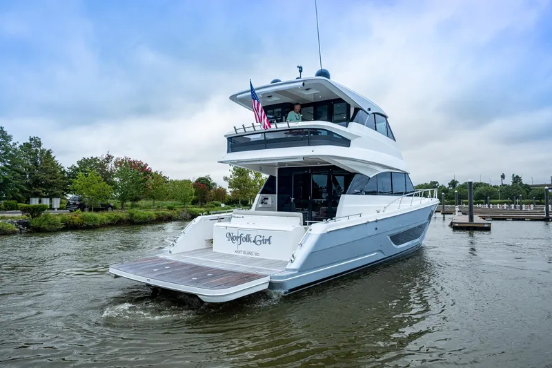 Norfolk Girl Yacht Photos Pics 2023 Maritimo M55 yacht cruising on a calm river near a marina.