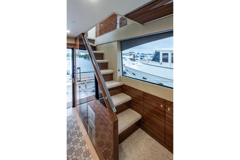 Norfolk Girl Yacht Photos Pics Interior of 2023 Maritimo M55 yacht with elegant wooden staircase and marina view.