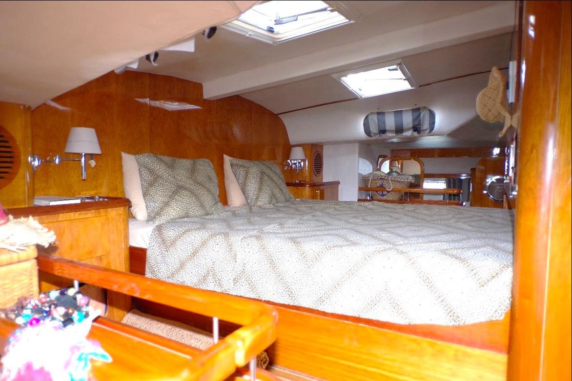 Luxurious cabin interior of 2004 Privilege 49 yacht with cozy bedding and wooden finishes.