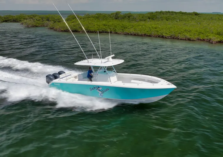 Baby Blues Yacht Photos Pics 2013 Bahama 37 boat speeding on water near lush green shoreline.