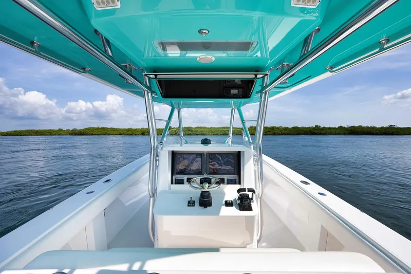 Baby Blues Yacht Photos Pics 2013 Bahama 37 boat cockpit with turquoise canopy, dual screens, and steering wheel on calm water.