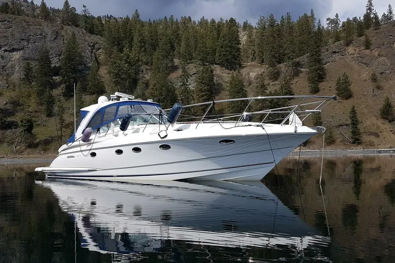  Yacht Photos Pics 2005 Doral Alegria yacht on calm water, surrounded by forested hills.