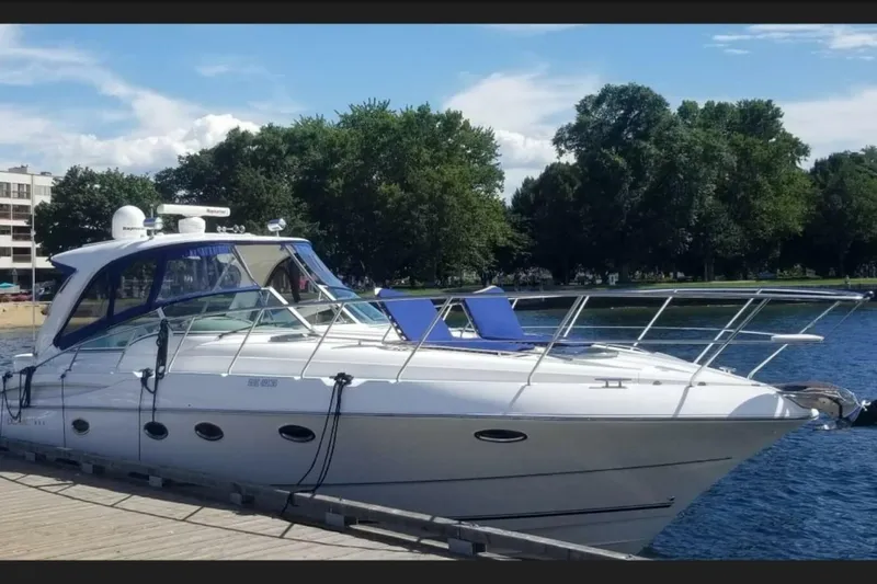  Yacht Photos Pics 2005 Doral Alegria yacht docked by a scenic waterfront with lush trees.