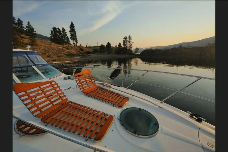  Yacht Photos Pics 2005 Doral Alegria yacht with wooden deck chairs on a serene lake at sunset.