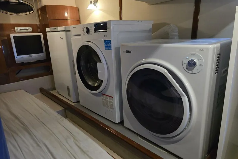  Yacht Photos Pics Laundry area inside a 2005 Doral Alegria boat with washer, dryer, and TV.