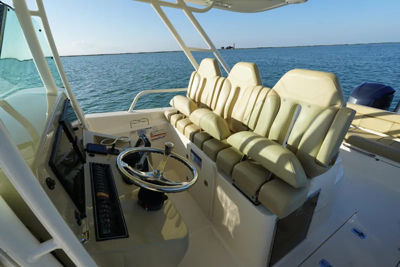  Yacht Photos Pics 2016 Pursuit ST 310 Sport boat interior with helm and seating, on calm water.