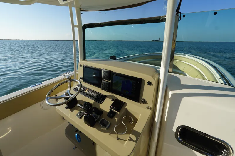  Yacht Photos Pics 2016 Pursuit ST 310 Sport boat dashboard with steering wheel and navigation screens on open water.