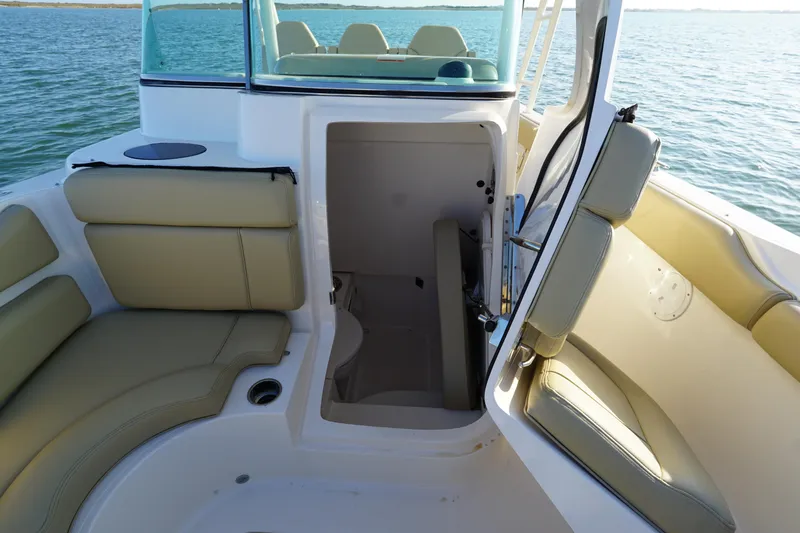  Yacht Photos Pics 2016 Pursuit ST 310 Sport boat interior with open cabin door, beige seating, and ocean view.