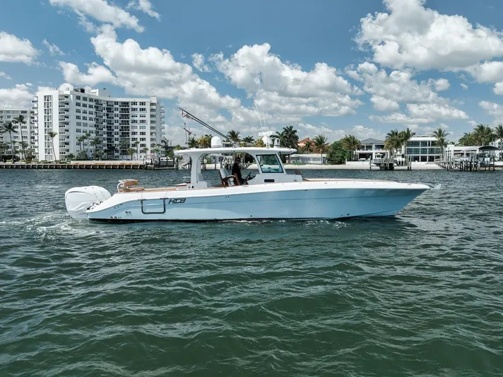 Mo Jack Yacht Photos Pics 2022 HCB Lujo boat cruising on a sunny day near waterfront buildings.
