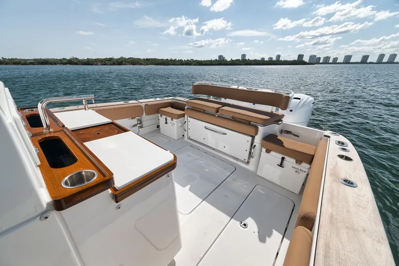 Mo Jack Yacht Photos Pics 2022 HCB Lujo boat deck with seating, overlooking calm waters and distant skyline.