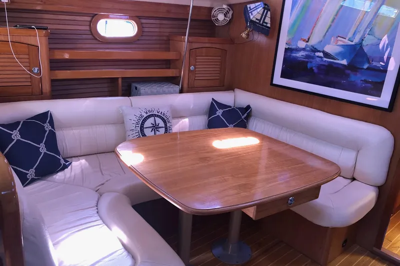Charmed Life Yacht Photos Pics Cozy interior of 2000 Catalina 470 yacht with wooden table and cushioned seating.