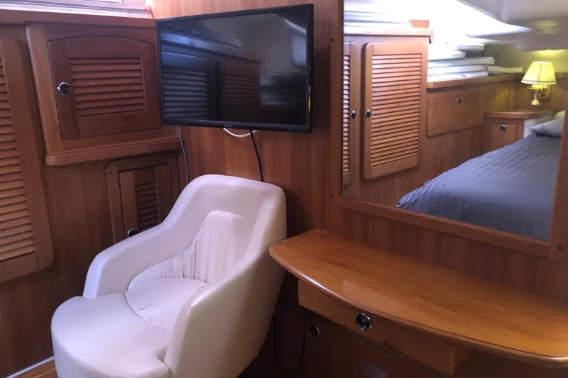 Charmed Life Yacht Photos Pics Interior of 2000 Catalina 470 yacht with chair, TV, and wooden cabinetry.