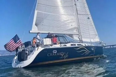 Charmed Life Yacht Photos Pics Sailing yacht Catalina 470, 2000 model, with American flag on open water.