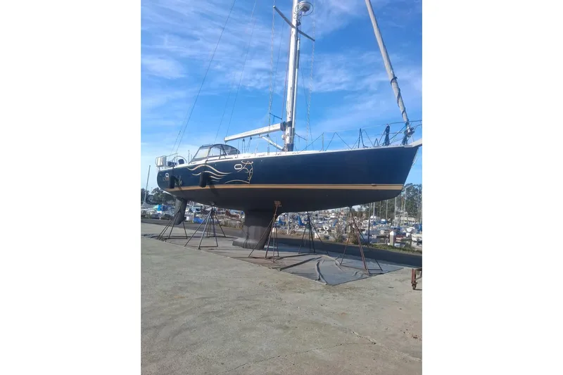 Charmed Life Yacht Photos Pics Catalina 470 sailboat from 2000 on dry dock, blue hull, clear sky background.