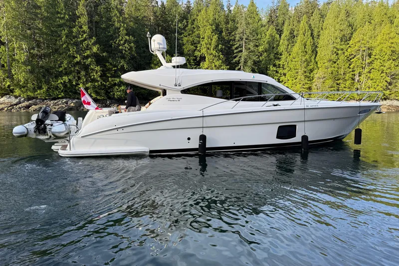 Dolce Far Niente Yacht Photos Pics 2012 Maritimo C53 Sports Cabriolet yacht on calm water, surrounded by lush forest.