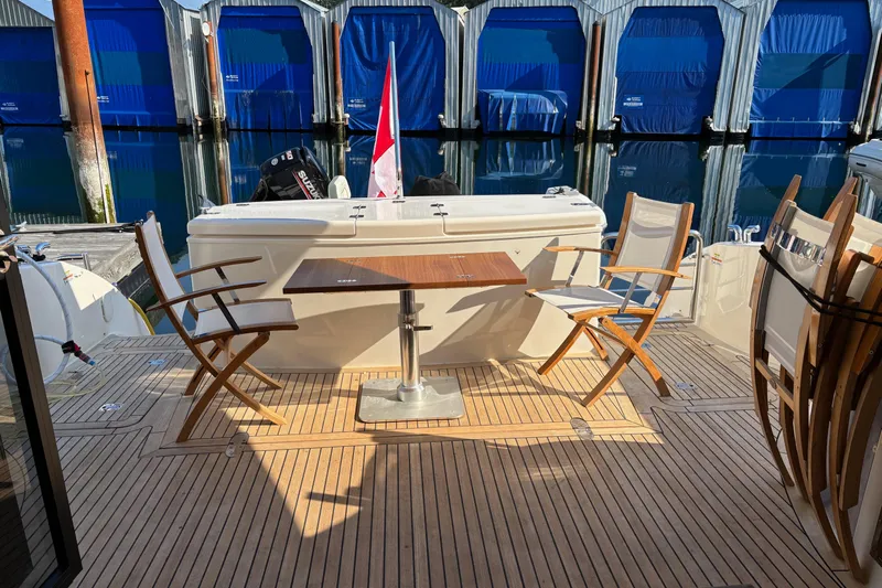 Dolce Far Niente Yacht Photos Pics 2012 Maritimo C53 Sports Cabriolet yacht deck with wooden chairs and table, docked at marina.
