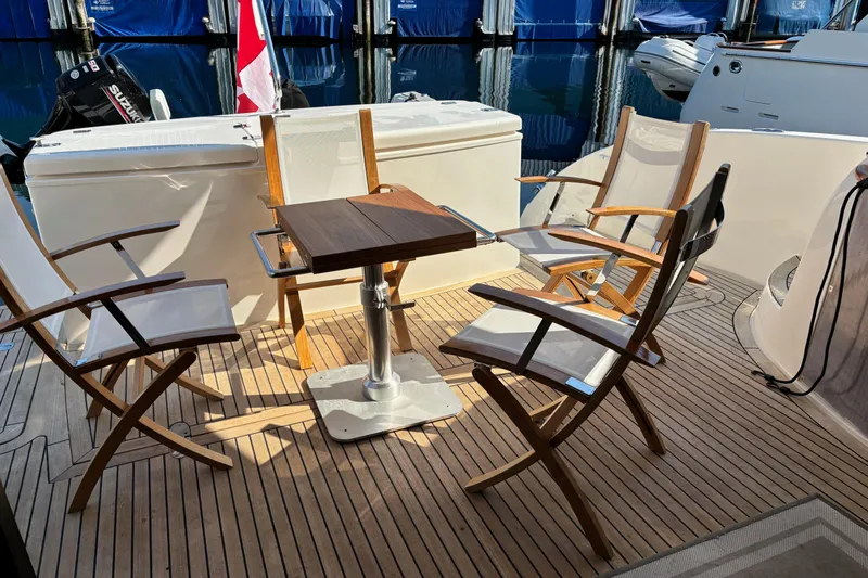 Dolce Far Niente Yacht Photos Pics Deck seating area on a 2012 Maritimo C53 Sports Cabriolet yacht with wooden chairs and table.