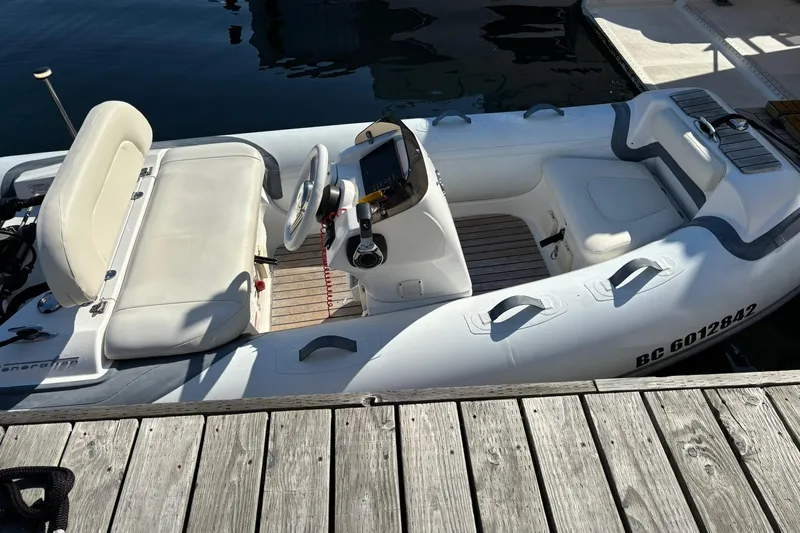 Dolce Far Niente Yacht Photos Pics Inflatable boat docked, featuring white seating and steering console, near wooden pier.